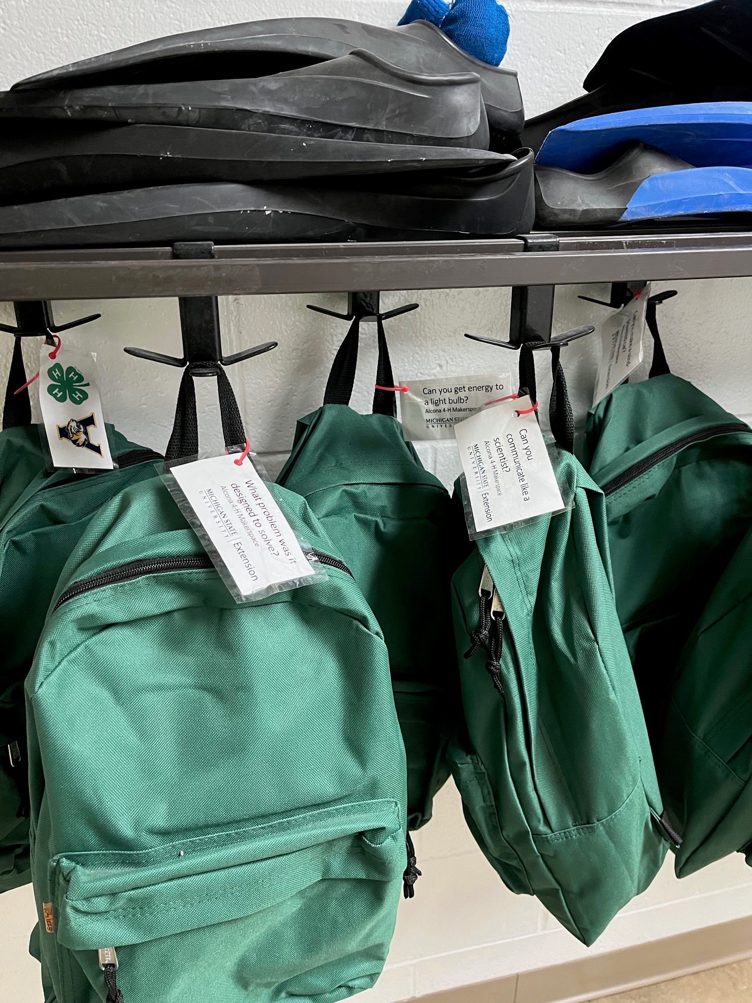 Green backpacks hanging on hooks